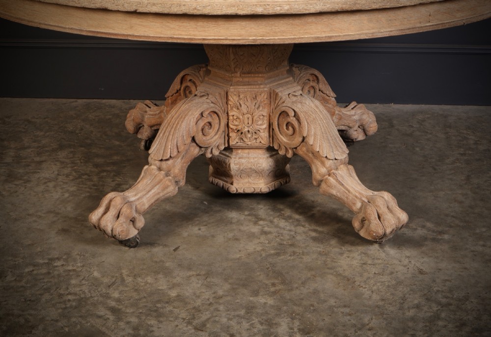 An oval bleached oak centre table featuring an intricately carved pedestal base with scroll legs and paw feet. View IV