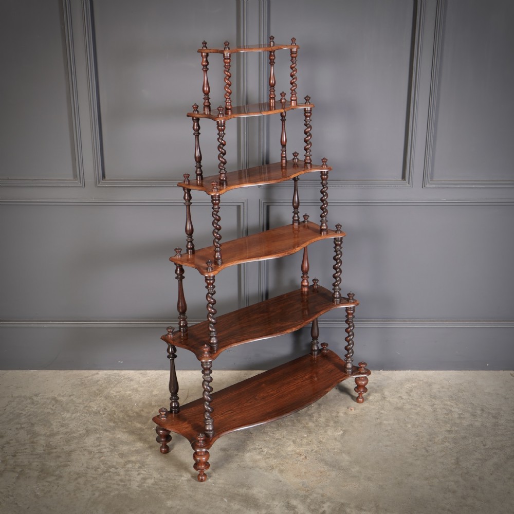 A Victorian rosewood six-tier whatnot stand featuring graduated open shelves supported by barley twist columns and topped with turned finials.