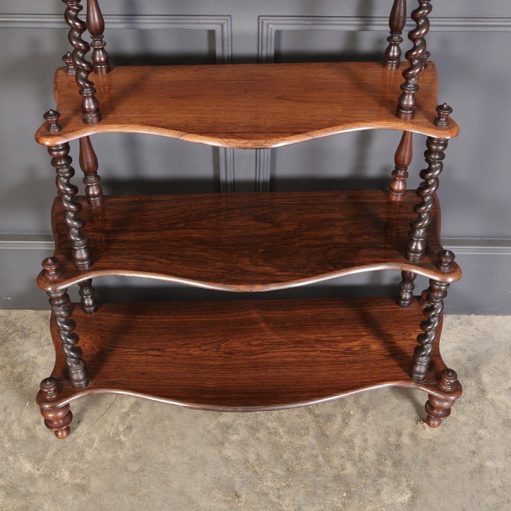 A Victorian rosewood six-tier whatnot stand featuring graduated open shelves supported by barley twist columns and topped with turned finials. View V