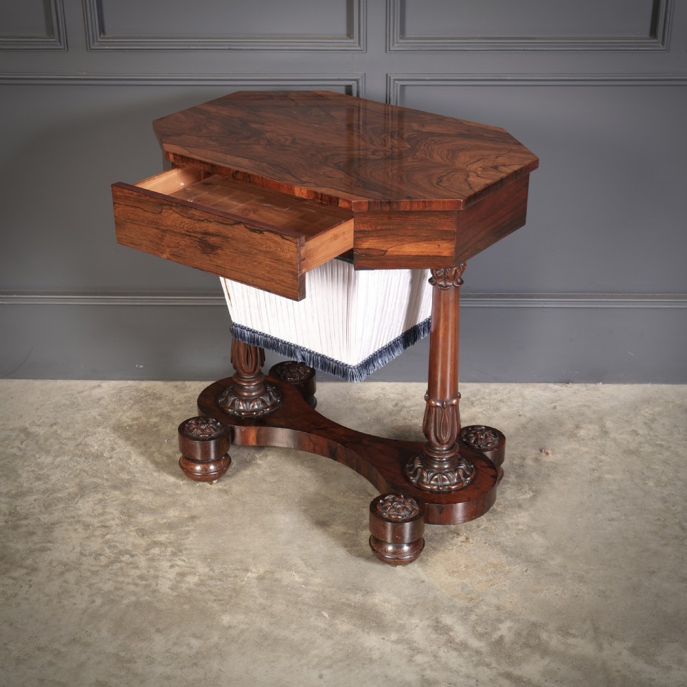 A William IV rosewood sewing table featuring an octagonal hinged top, a pleated fabric work basket, and carved twin column supports on a plinth base. View III