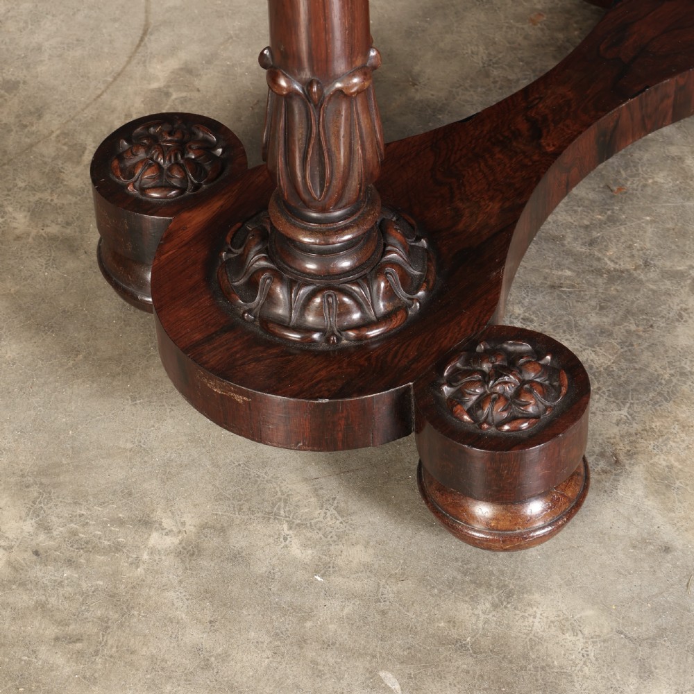 A William IV rosewood sewing table featuring an octagonal hinged top, a pleated fabric work basket, and carved twin column supports on a plinth base. View V