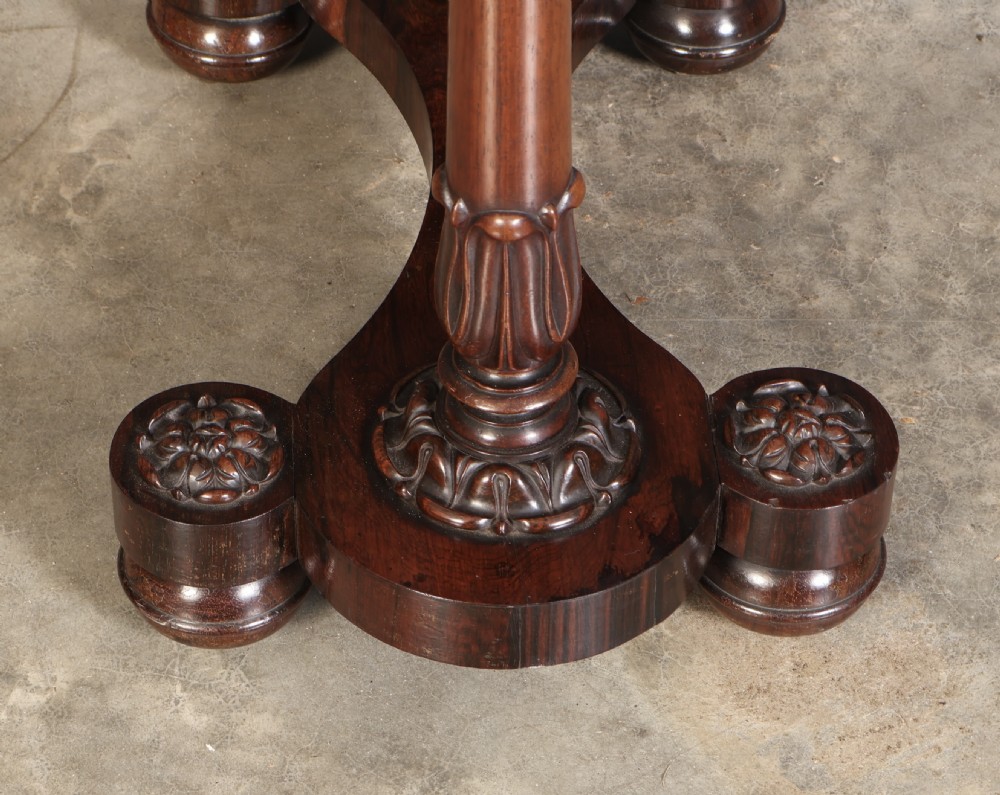 A William IV rosewood sewing table featuring an octagonal hinged top, a pleated fabric work basket, and carved twin column supports on a plinth base. View X