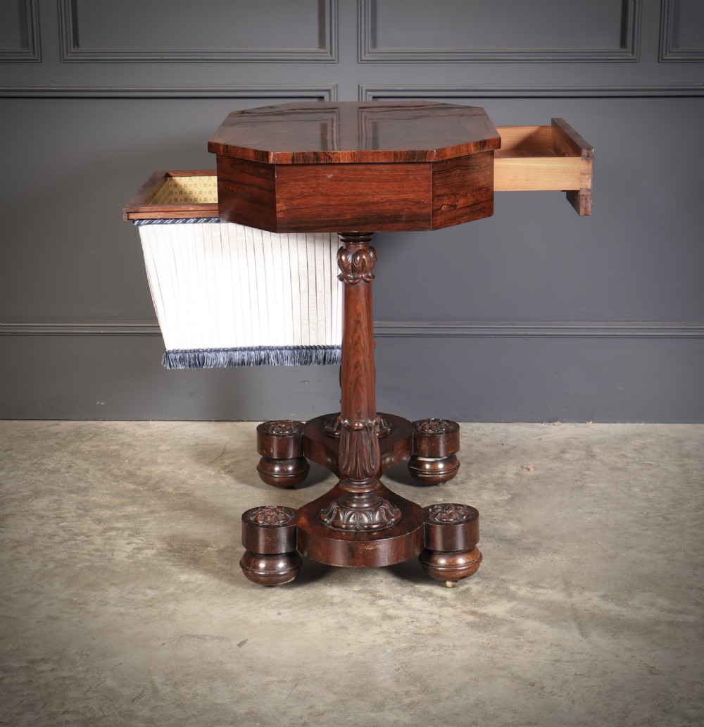 A William IV rosewood sewing table featuring an octagonal hinged top, a pleated fabric work basket, and carved twin column supports on a plinth base. View XIII