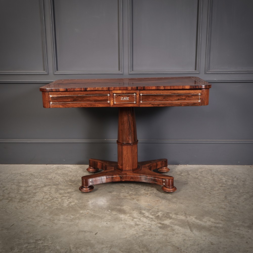 A Regency rosewood library table featuring brass stringing, dot inlays, frieze drawers, and a central pedestal support on a four-star base. View II