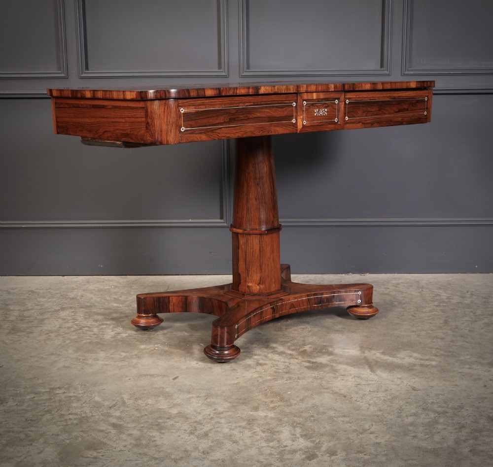 A Regency rosewood library table featuring brass stringing, dot inlays, frieze drawers, and a central pedestal support on a four-star base. View V