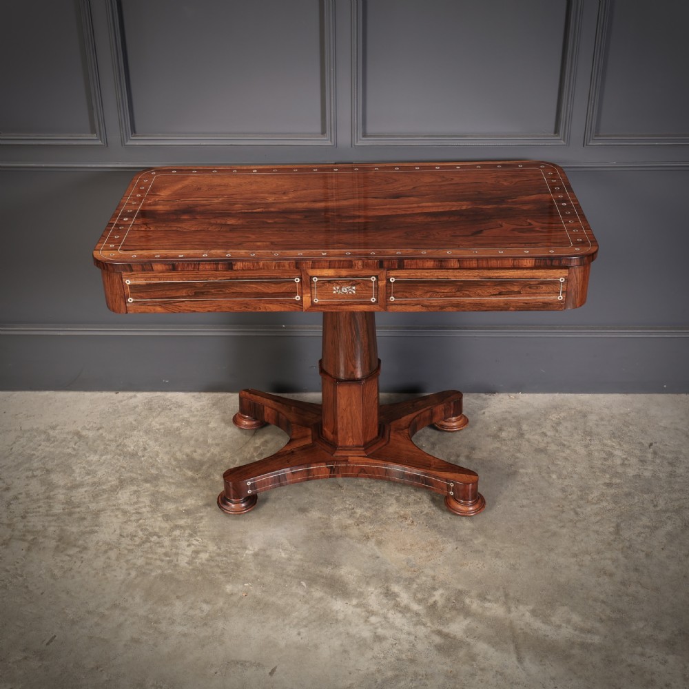 A Regency rosewood library table featuring brass stringing, dot inlays, frieze drawers, and a central pedestal support on a four-star base. View VII