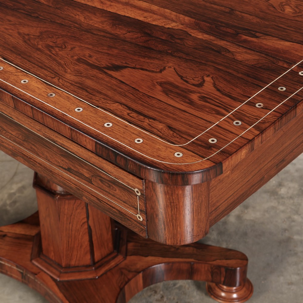 A Regency rosewood library table featuring brass stringing, dot inlays, frieze drawers, and a central pedestal support on a four-star base. View VIII