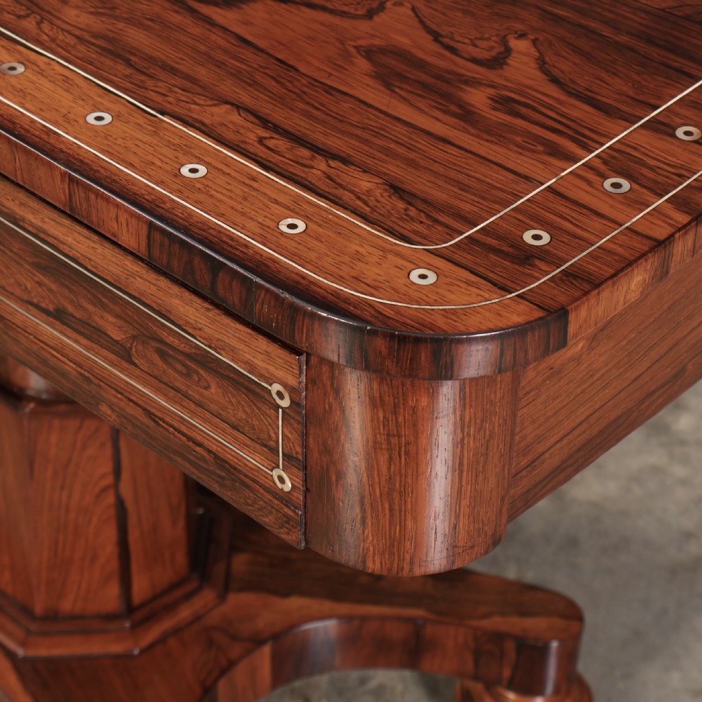 A Regency rosewood library table featuring brass stringing, dot inlays, frieze drawers, and a central pedestal support on a four-star base. View XI