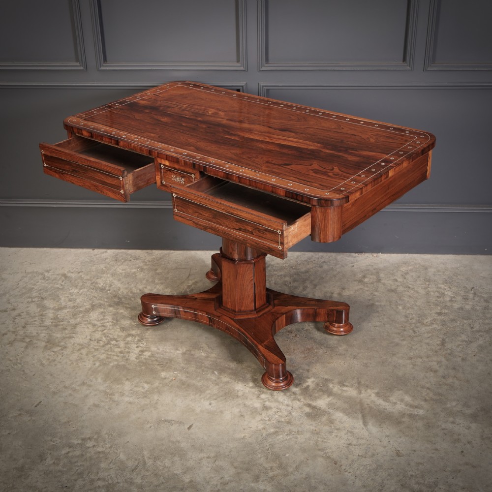 A Regency rosewood library table featuring brass stringing, dot inlays, frieze drawers, and a central pedestal support on a four-star base. View XII