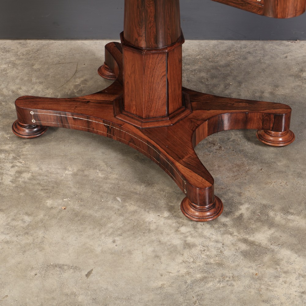 A Regency rosewood library table featuring brass stringing, dot inlays, frieze drawers, and a central pedestal support on a four-star base. View XIV