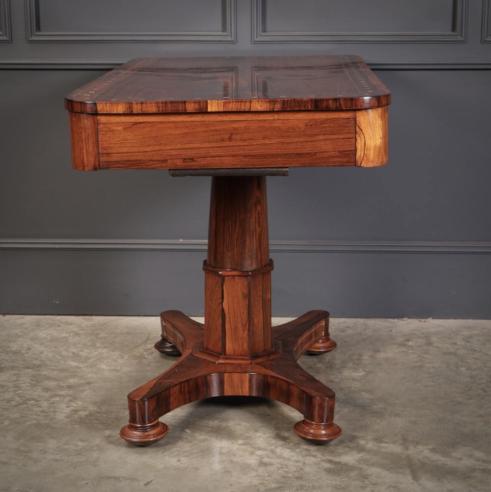 A Regency rosewood library table featuring brass stringing, dot inlays, frieze drawers, and a central pedestal support on a four-star base. View XV