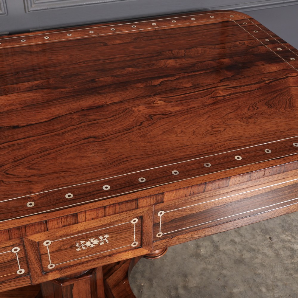 A Regency rosewood library table featuring brass stringing, dot inlays, frieze drawers, and a central pedestal support on a four-star base. View XVII