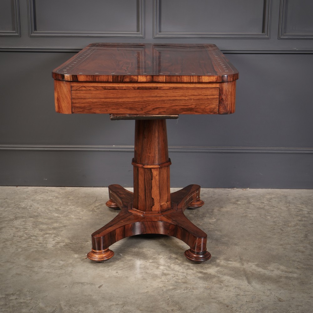A Regency rosewood library table featuring brass stringing, dot inlays, frieze drawers, and a central pedestal support on a four-star base. View XVIII