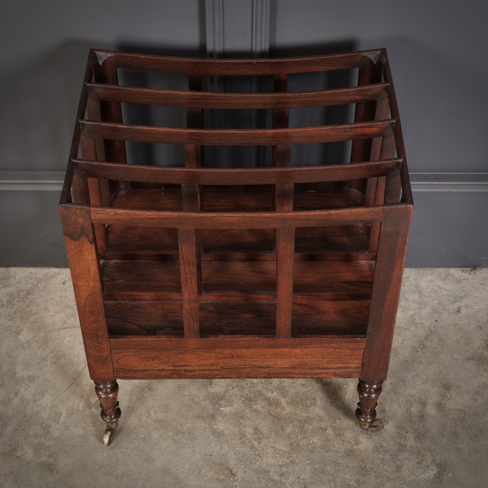 A William IV rosewood canterbury featuring four vertical slatted compartments, a single base drawer, turned legs, and brass castors. View II