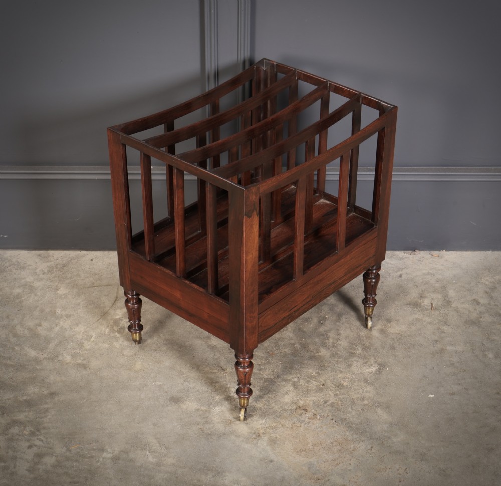 A William IV rosewood canterbury featuring four vertical slatted compartments, a single base drawer, turned legs, and brass castors. View III