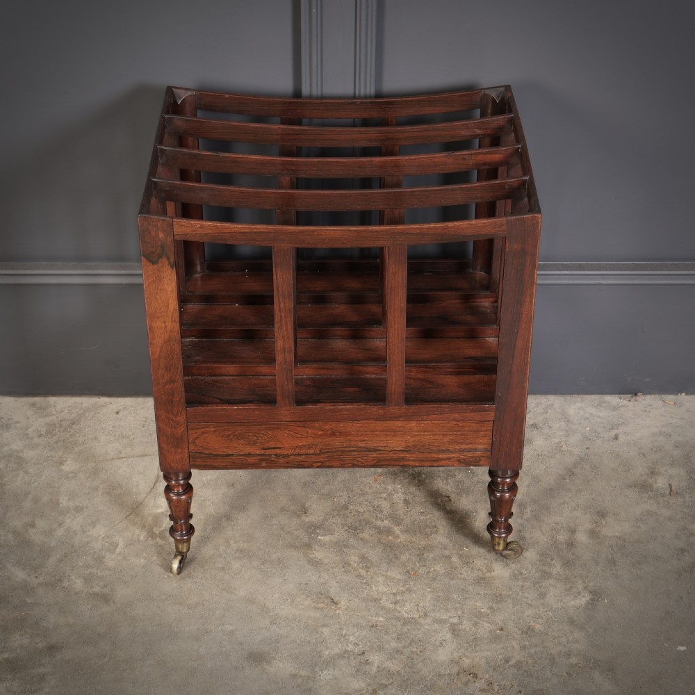 A William IV rosewood canterbury featuring four vertical slatted compartments, a single base drawer, turned legs, and brass castors. View V