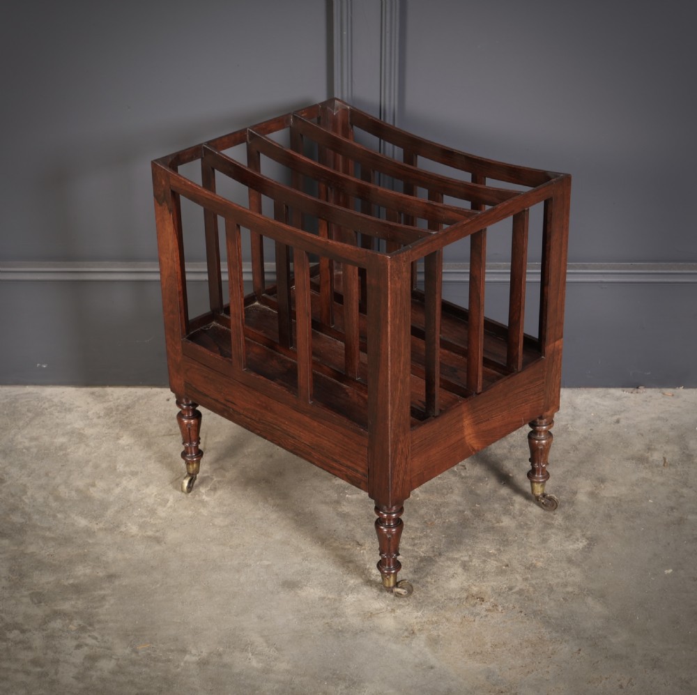 A William IV rosewood canterbury featuring four vertical slatted compartments, a single base drawer, turned legs, and brass castors. View VI