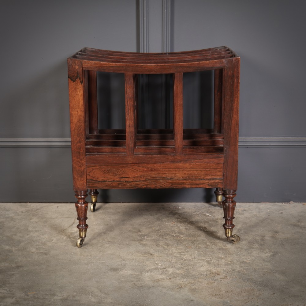 A William IV rosewood canterbury featuring four vertical slatted compartments, a single base drawer, turned legs, and brass castors. View VII