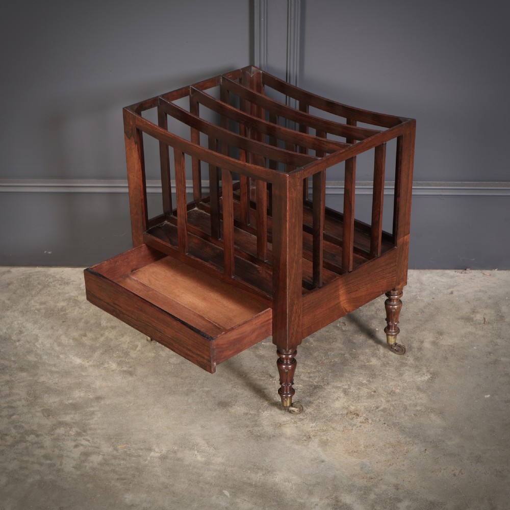 A William IV rosewood canterbury featuring four vertical slatted compartments, a single base drawer, turned legs, and brass castors. View VIII