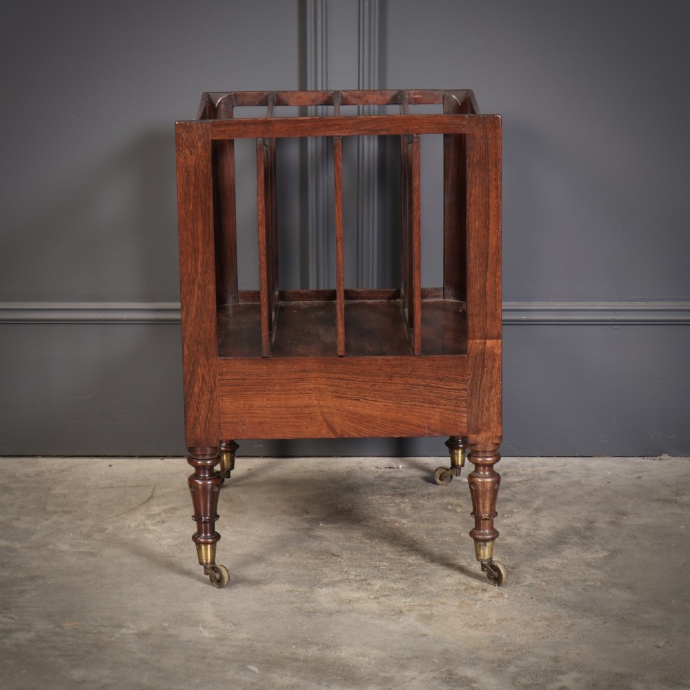 A William IV rosewood canterbury featuring four vertical slatted compartments, a single base drawer, turned legs, and brass castors. View IX