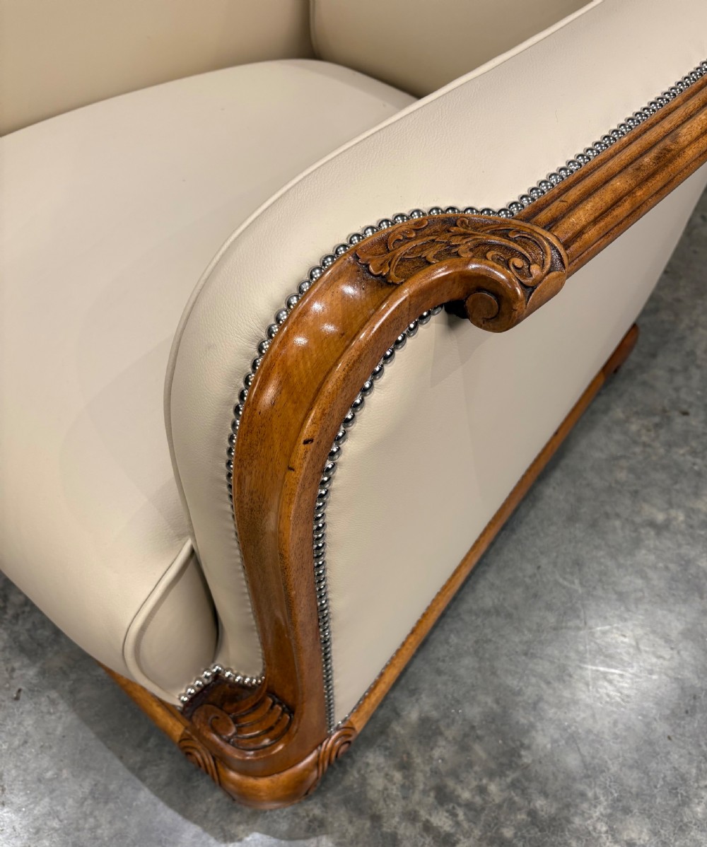 A pair of Art Deco armchairs featuring cream leather upholstery, polished walnut arm supports with scroll details, and metal studwork trim. View III