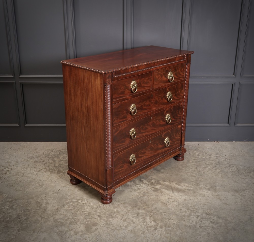 A nineteenth-century Scottish flame mahogany chest of drawers featuring twist-turned side columns, five graduated drawers with brass ring handles, and turned feet. View II