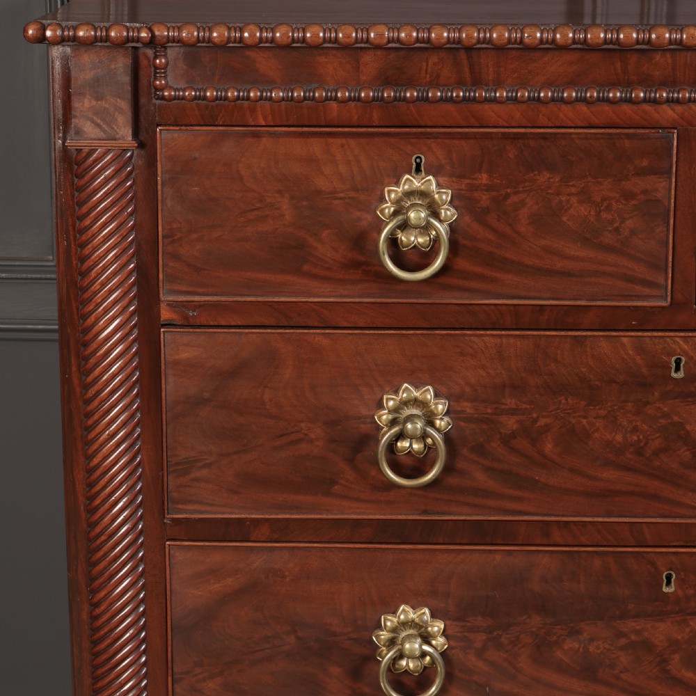 A nineteenth-century Scottish flame mahogany chest of drawers featuring twist-turned side columns, five graduated drawers with brass ring handles, and turned feet. View VII