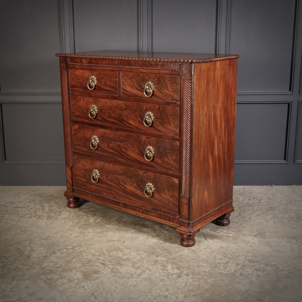 A nineteenth-century Scottish flame mahogany chest of drawers featuring twist-turned side columns, five graduated drawers with brass ring handles, and turned feet. View X