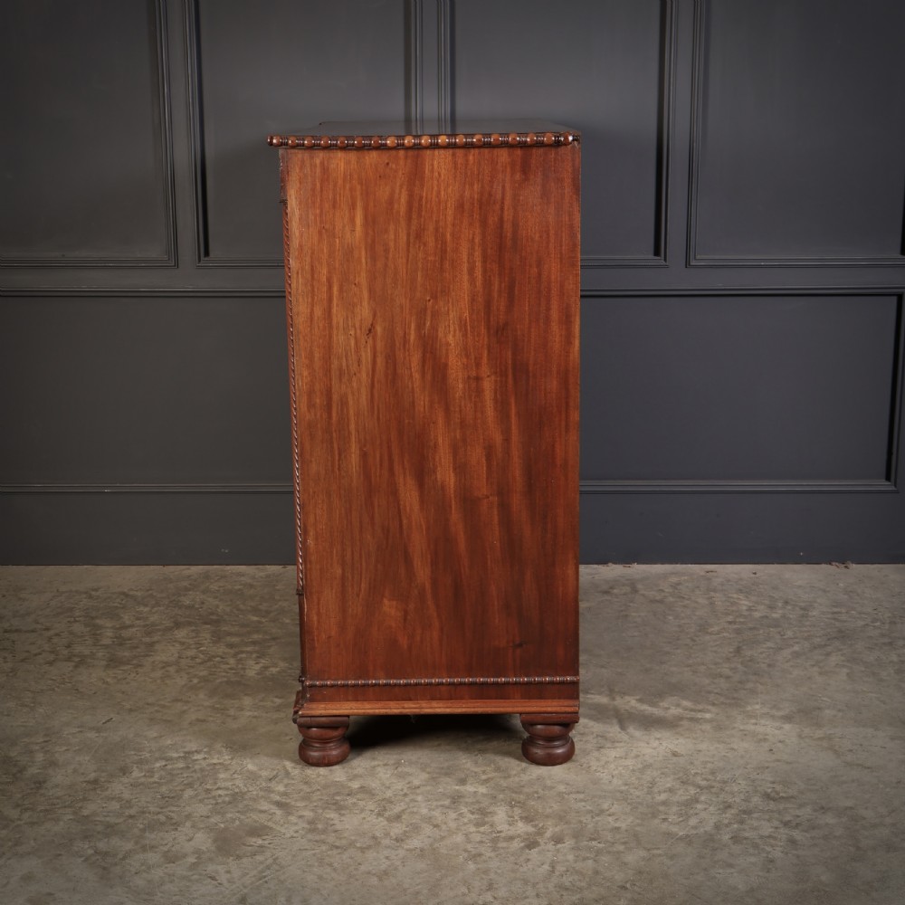 A nineteenth-century Scottish flame mahogany chest of drawers featuring twist-turned side columns, five graduated drawers with brass ring handles, and turned feet. View XIII