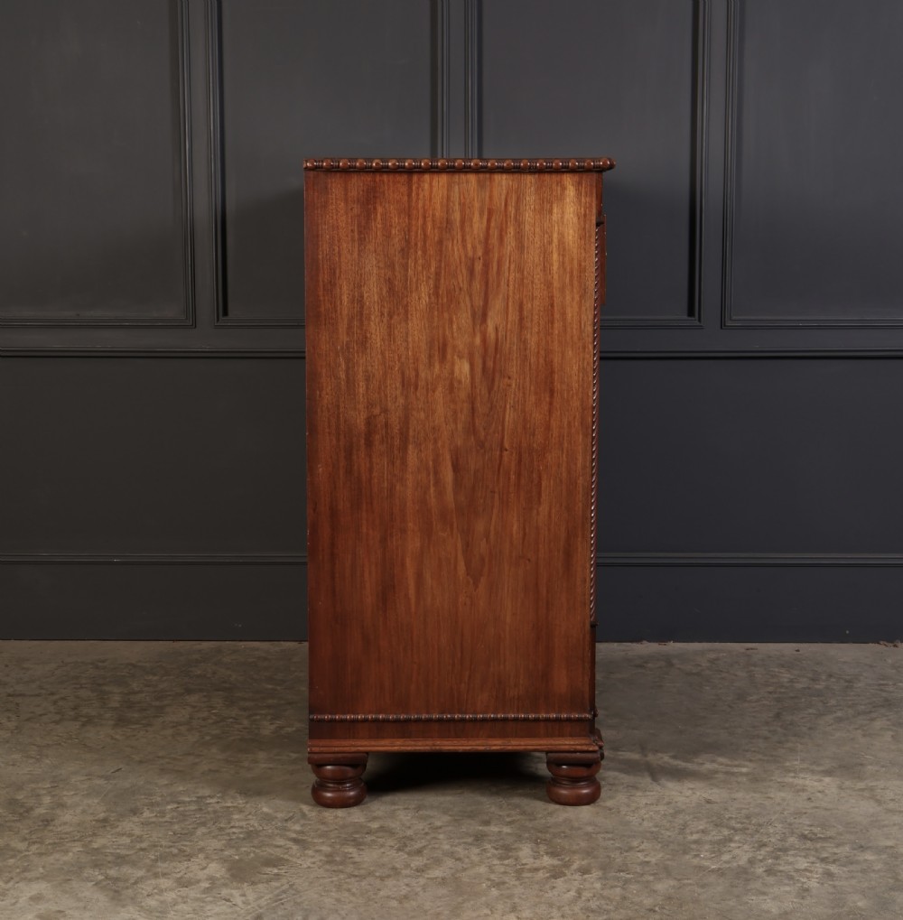 A nineteenth-century Scottish flame mahogany chest of drawers featuring twist-turned side columns, five graduated drawers with brass ring handles, and turned feet. View XV