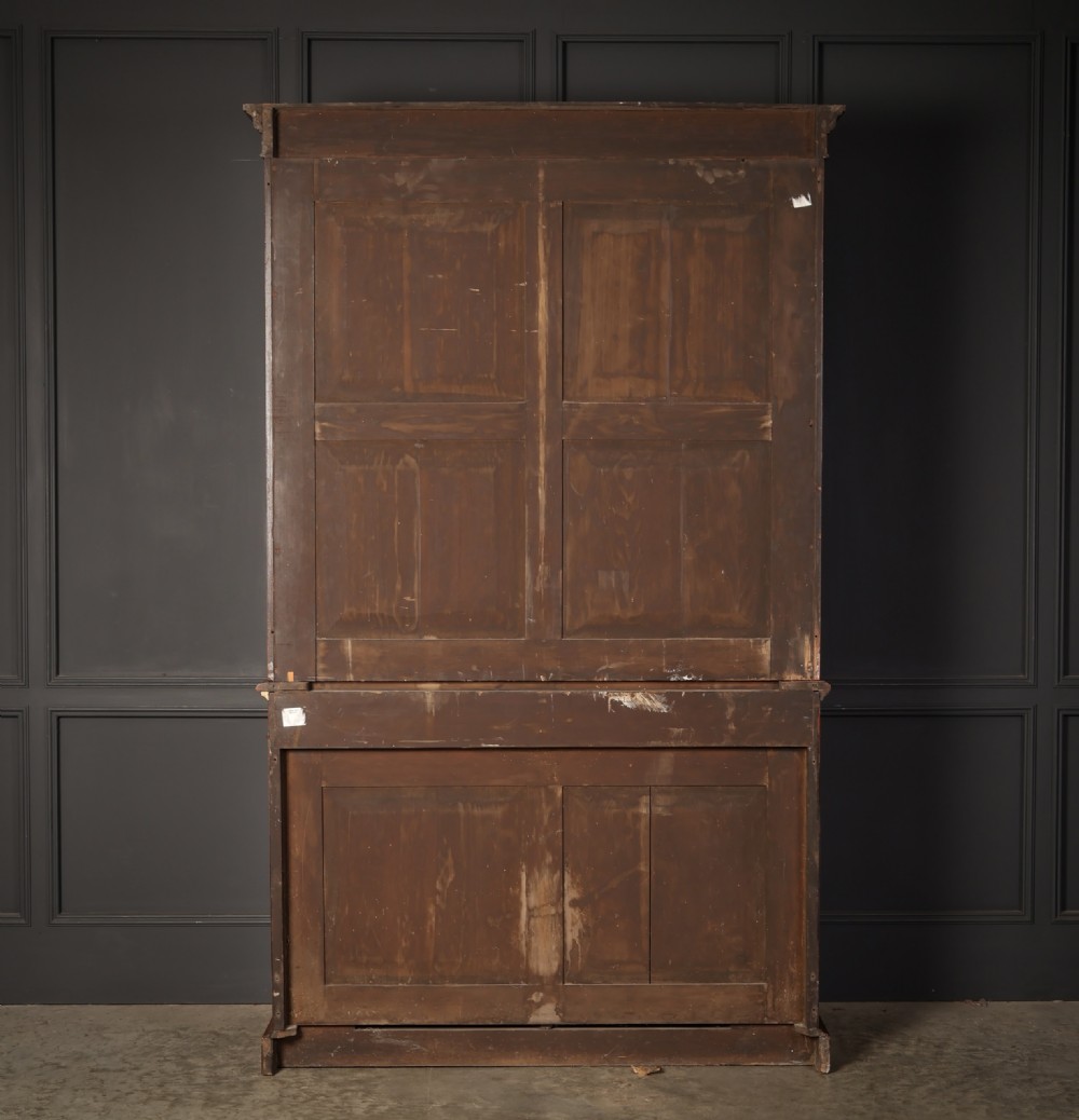 A two-part William IV walnut bookcase featuring upper and lower glazed doors with carved corbel accents and a plinth base. View XV