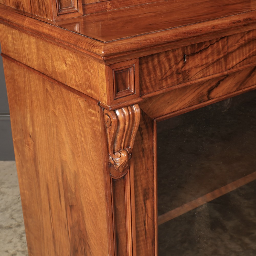 A two-part William IV walnut bookcase featuring upper and lower glazed doors with carved corbel accents and a plinth base. View XVIII