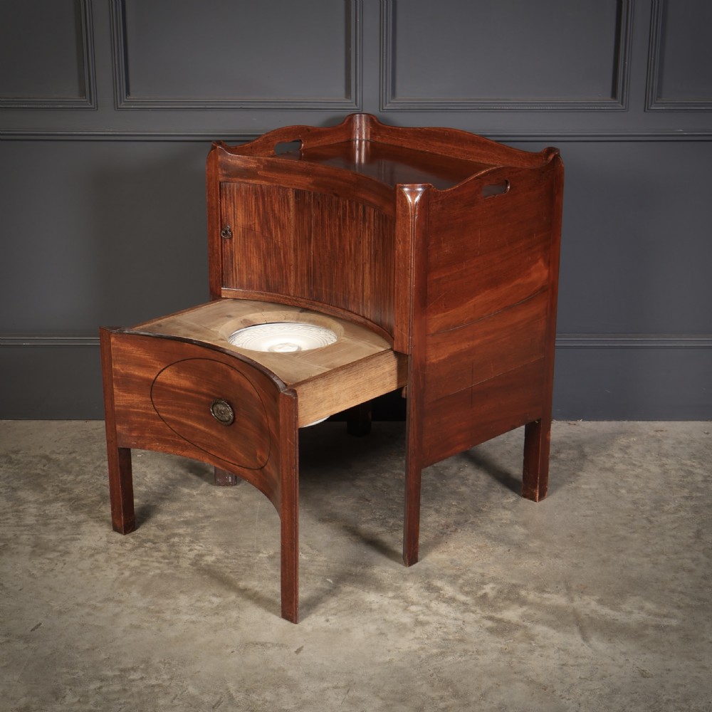 A George III mahogany nightstand featuring a gallery top, concave front with a tambour door, and a single lower drawer with oval inlay. View II