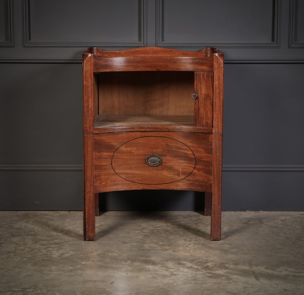 A George III mahogany nightstand featuring a gallery top, concave front with a tambour door, and a single lower drawer with oval inlay. View III