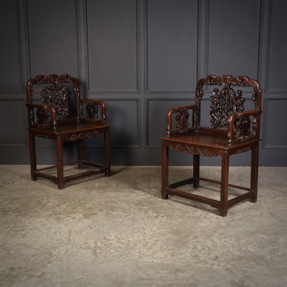 A pair of traditional Chinese dark hardwood Hongmu armchairs with intricately carved openwork back panels and rectangular seats. View II