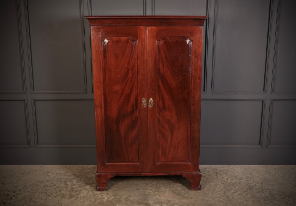 A George III mahogany estate cabinet shown with open panelled doors, revealing an interior with shelves on one side and multiple fitted drawers with brass ring handles on the other. View II