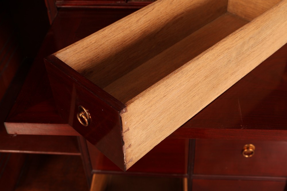 A George III mahogany estate cabinet shown with open panelled doors, revealing an interior with shelves on one side and multiple fitted drawers with brass ring handles on the other. View VI