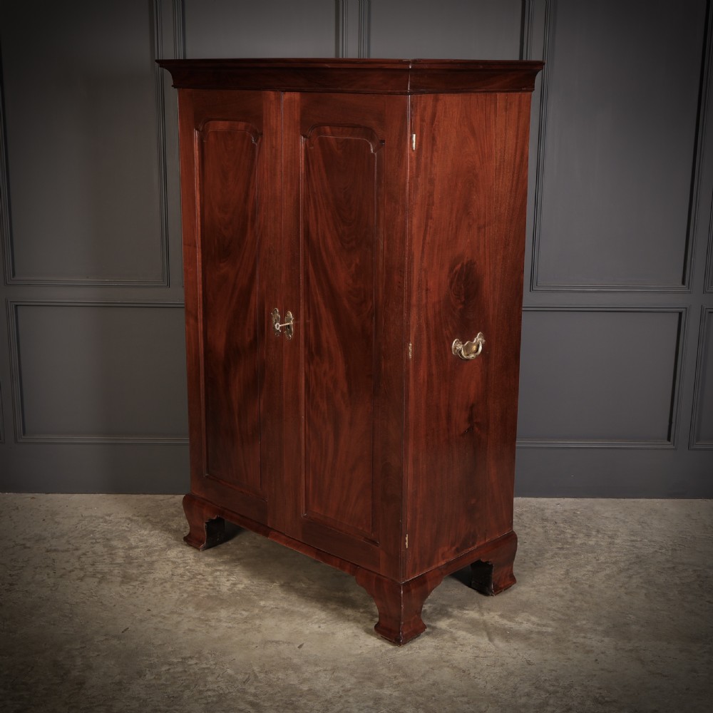 A George III mahogany estate cabinet shown with open panelled doors, revealing an interior with shelves on one side and multiple fitted drawers with brass ring handles on the other. View VII