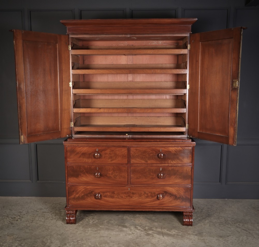 A nineteenth-century Scottish flame mahogany linen press featuring a upper double-door cupboard with side columns above a four-drawer base with carved bracket feet. View VII