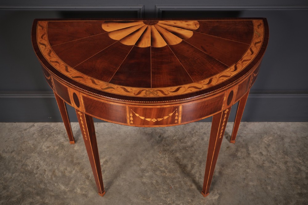 An 18th-century demilune tea table made of dark mahogany with satinwood marquetry inlays featuring a fan motif and tapered legs. View II