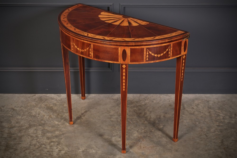 An 18th-century demilune tea table made of dark mahogany with satinwood marquetry inlays featuring a fan motif and tapered legs. View V