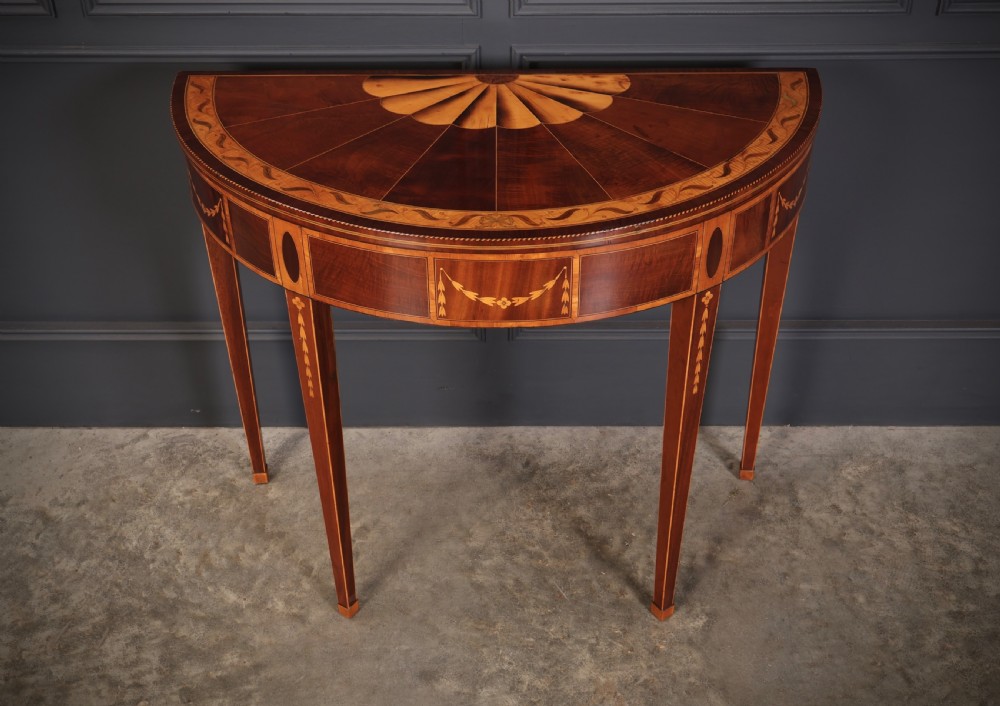 An 18th-century demilune tea table made of dark mahogany with satinwood marquetry inlays featuring a fan motif and tapered legs. View VI