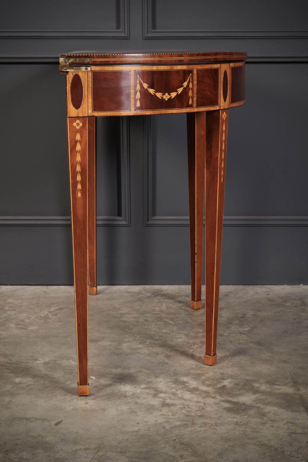 An 18th-century demilune tea table made of dark mahogany with satinwood marquetry inlays featuring a fan motif and tapered legs. View XII