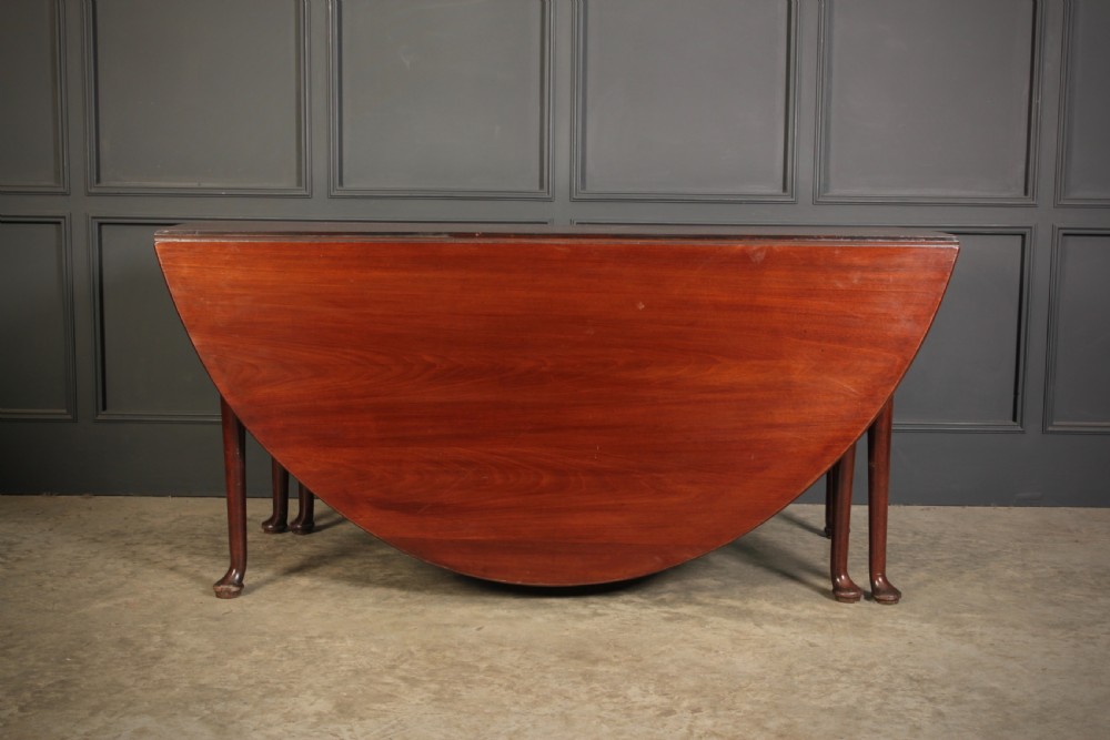 An 18th-century Georgian mahogany drop-leaf dining table with an oval top supported by tapered legs with pad feet. View II