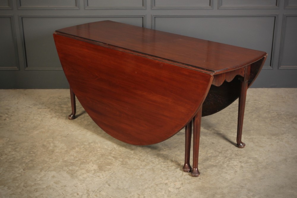An 18th-century Georgian mahogany drop-leaf dining table with an oval top supported by tapered legs with pad feet. View V