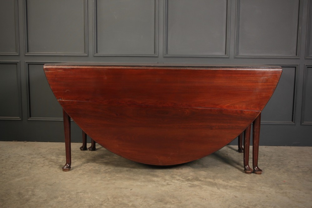 An 18th-century Georgian mahogany drop-leaf dining table with an oval top supported by tapered legs with pad feet. View VII