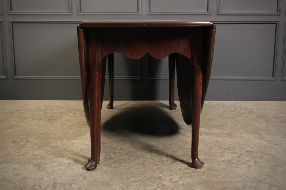 An 18th-century Georgian mahogany drop-leaf dining table with an oval top supported by tapered legs with pad feet. View VIII