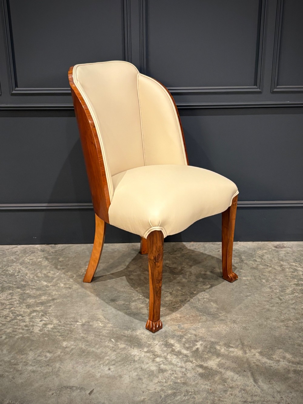 A pair of Art Deco armchairs featuring curved walnut veneer frames and cream leather upholstery. View III