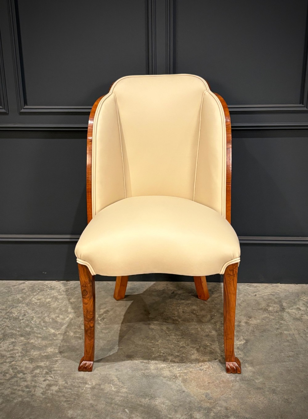 A pair of Art Deco armchairs featuring curved walnut veneer frames and cream leather upholstery. View VII