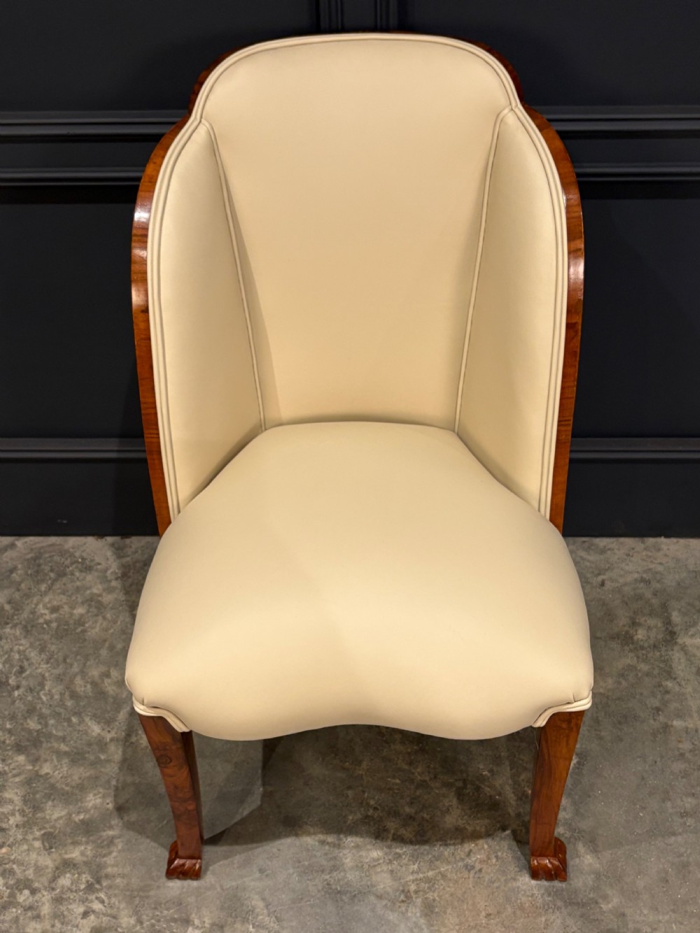 A pair of Art Deco armchairs featuring curved walnut veneer frames and cream leather upholstery. View VIII